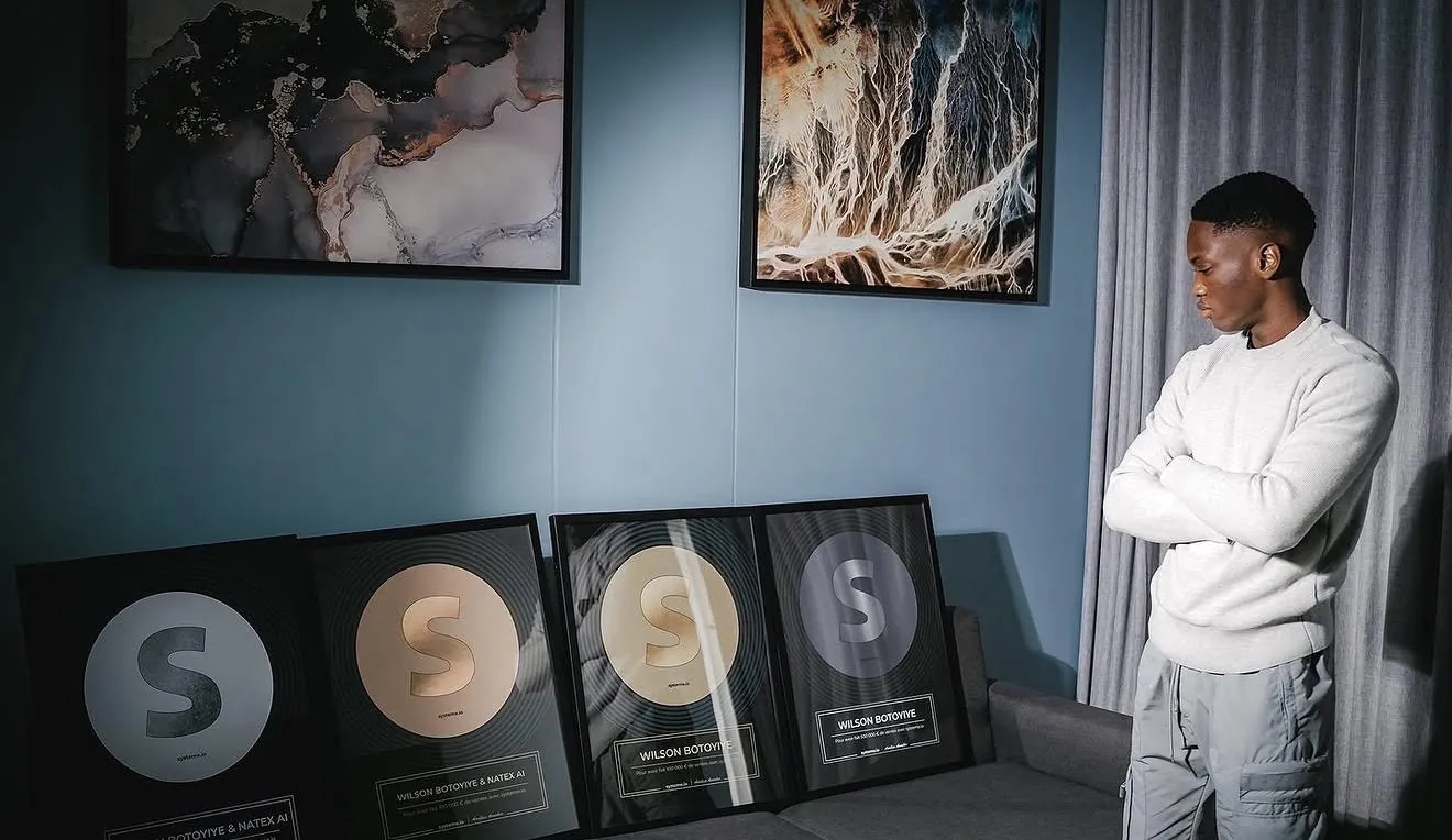 Wilson BOTOYIYE à côté de ses plaques de distinction.