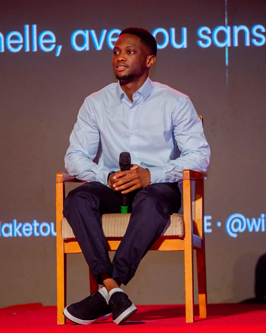Wilson BOTOYIYE assis sur scène, en pleine intervention.